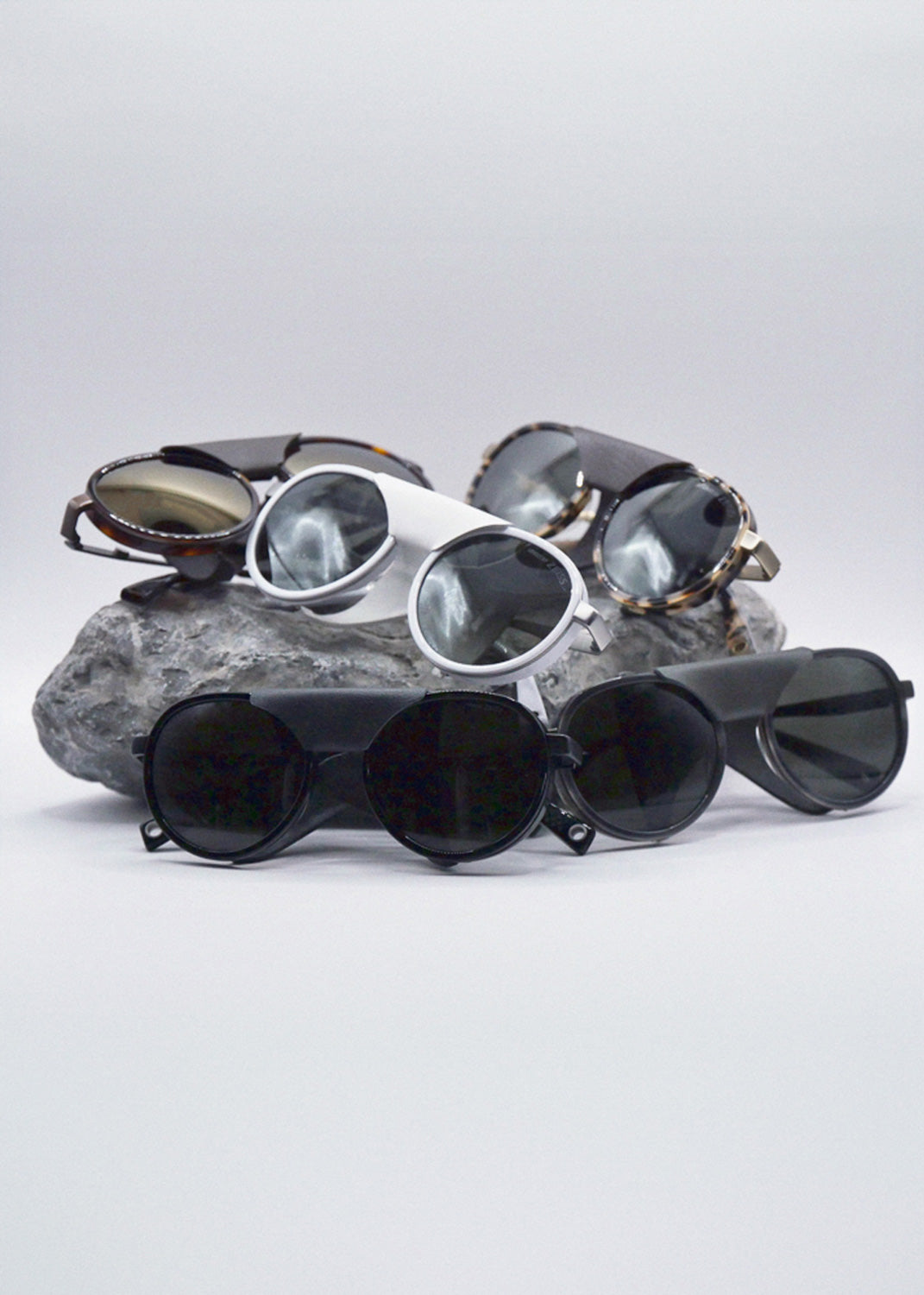 A pile of glacier sunglasses on top of a rock