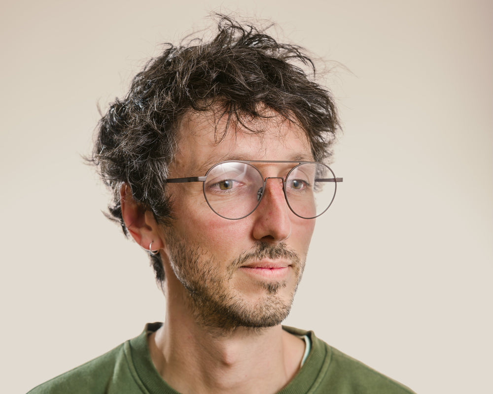 Man wearing a green sweatshirt with a logo on a plain background