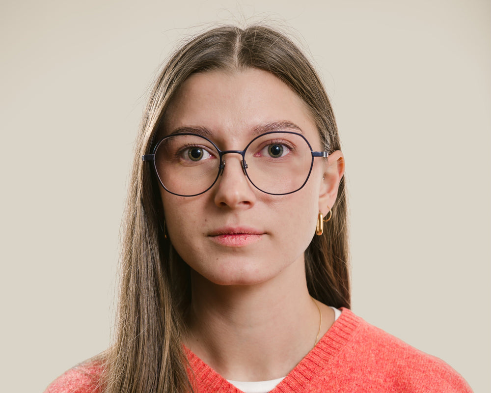 Person wearing a red sweater with a small logo on a plain background