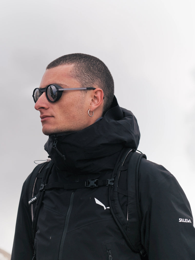 A man wearing palü bold grey mountaineering sunglasses in the mountain area 