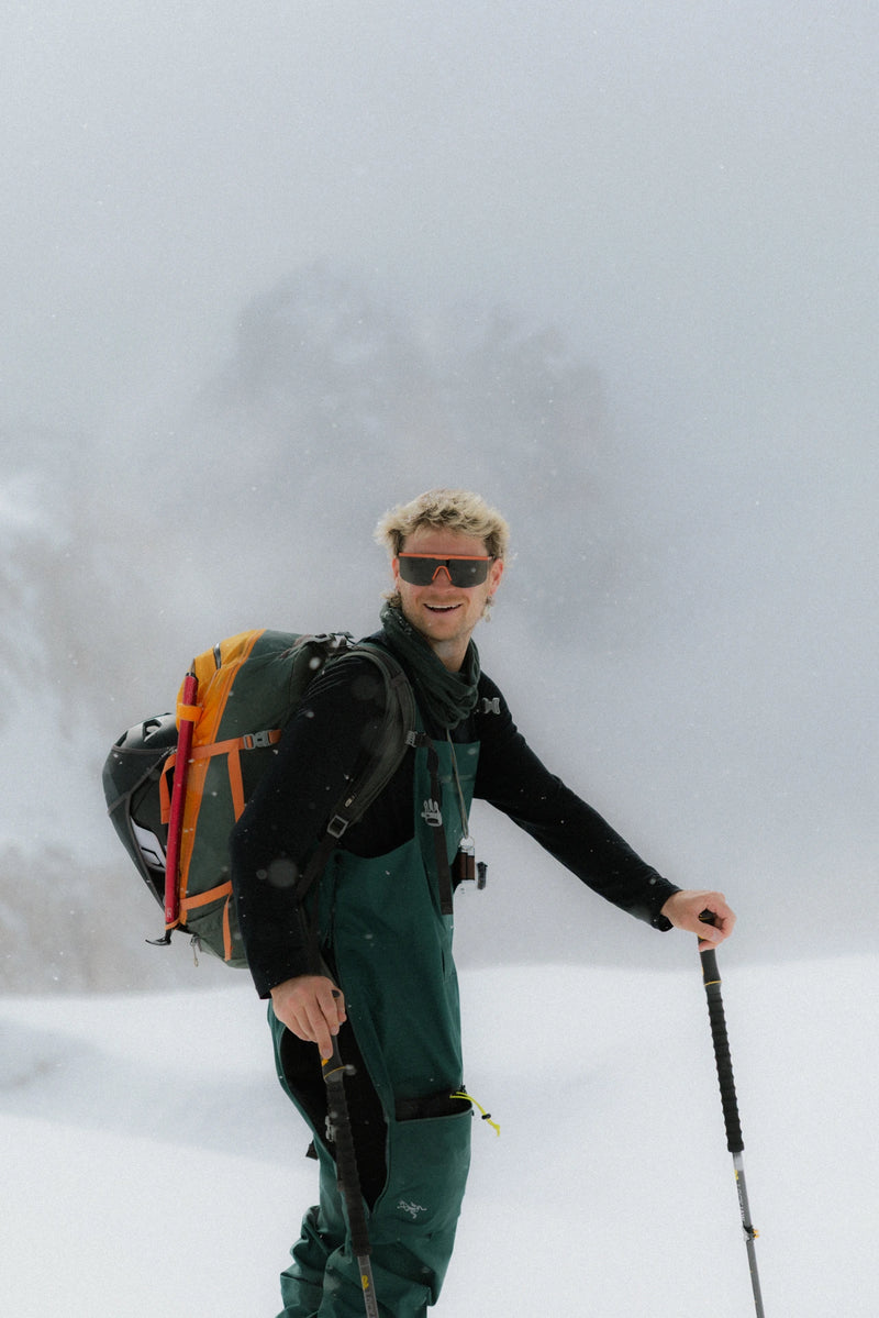 Person hiking in a snowy landscape with Pierredar in brick color and ski poles.