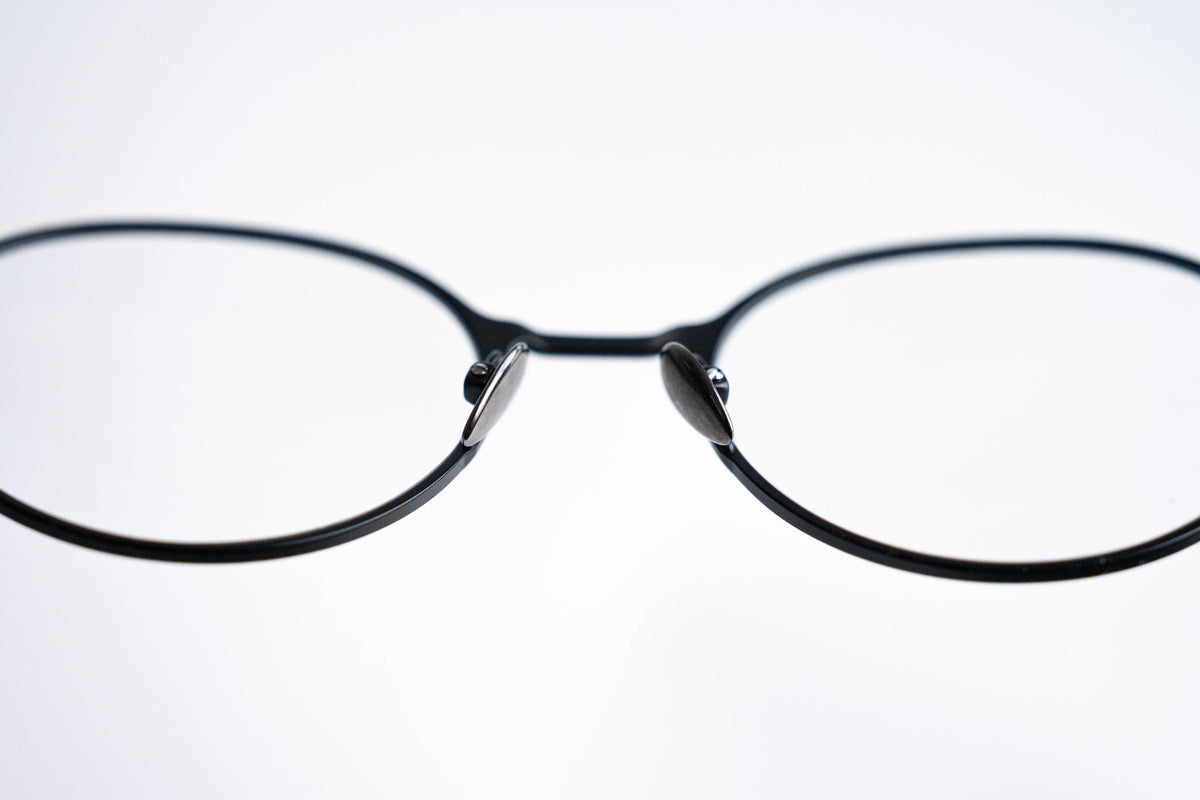 Close-up of a pair of round black titanium eyeglasses on a white background