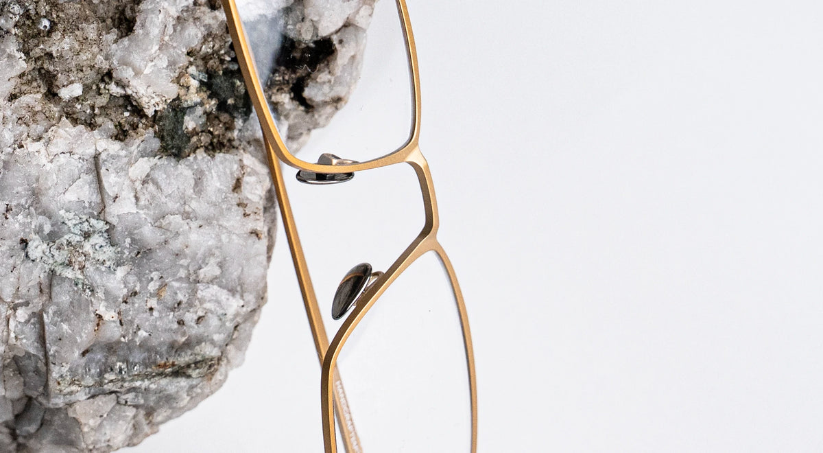 Gold titanium eyelasses on a rock surface