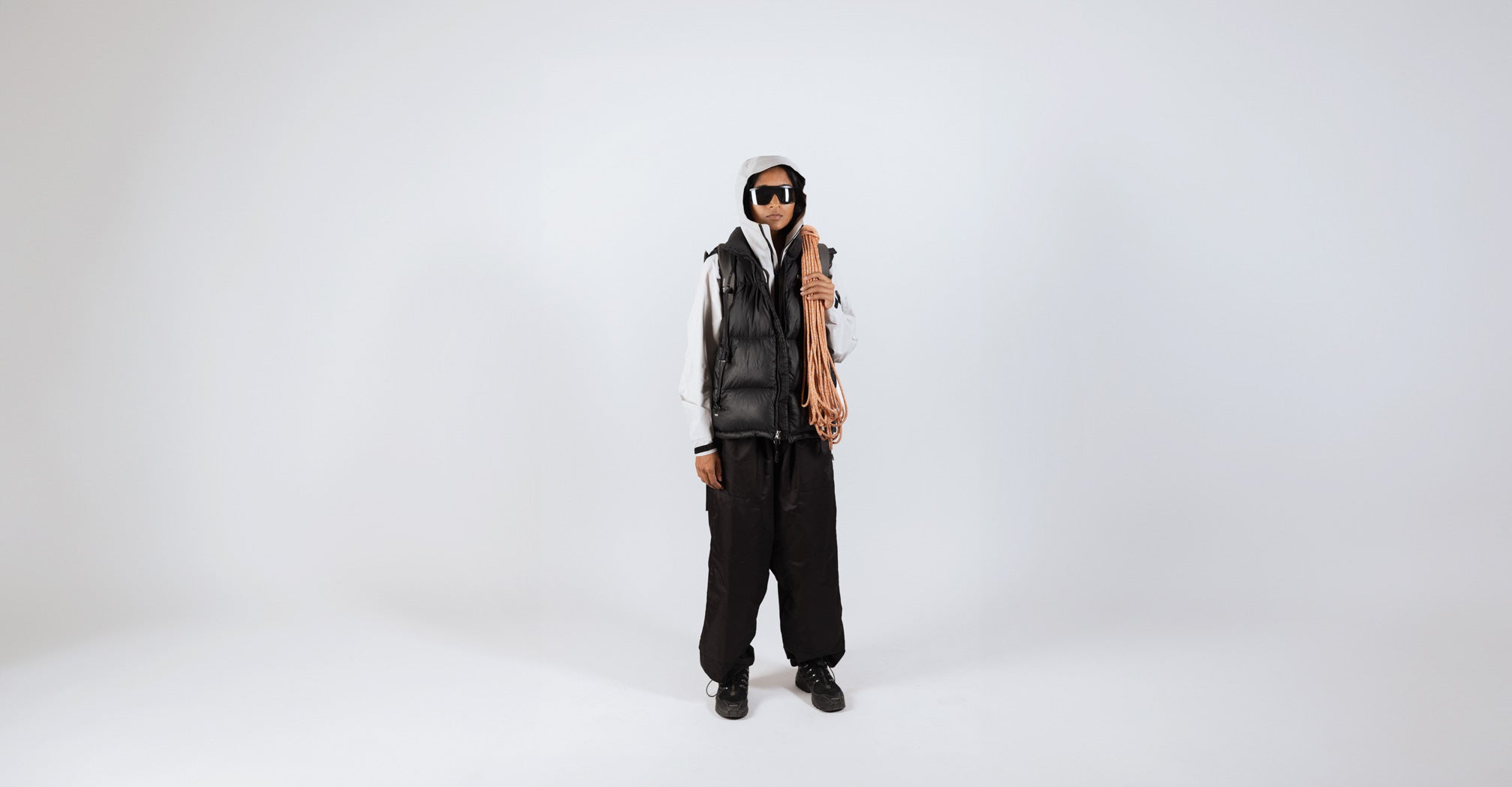 Woman with Glacier sunglasses and an alpinist cord with a white studio background