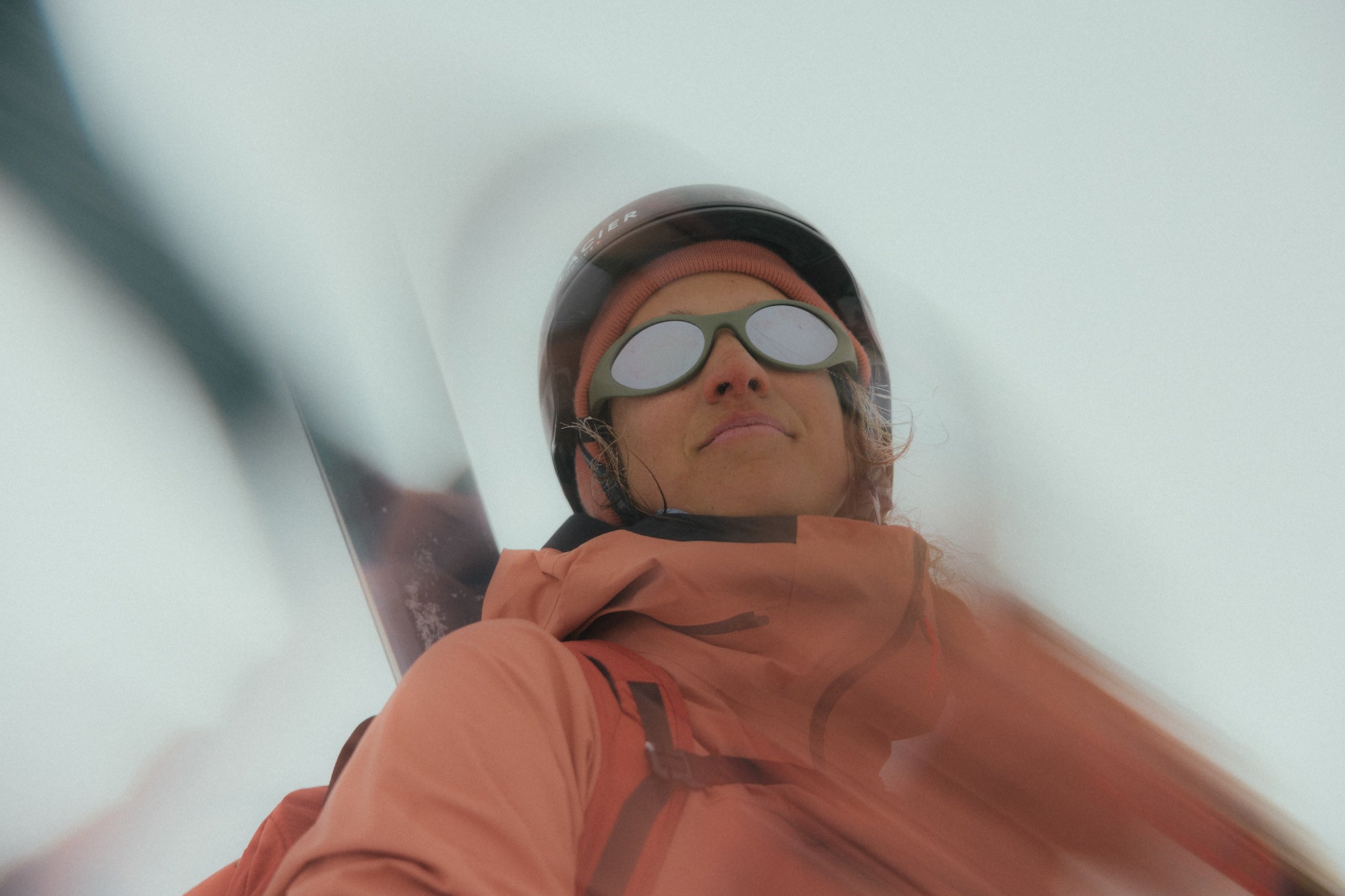 Person with an orange jacket and glacier sunglasses in a snow storm